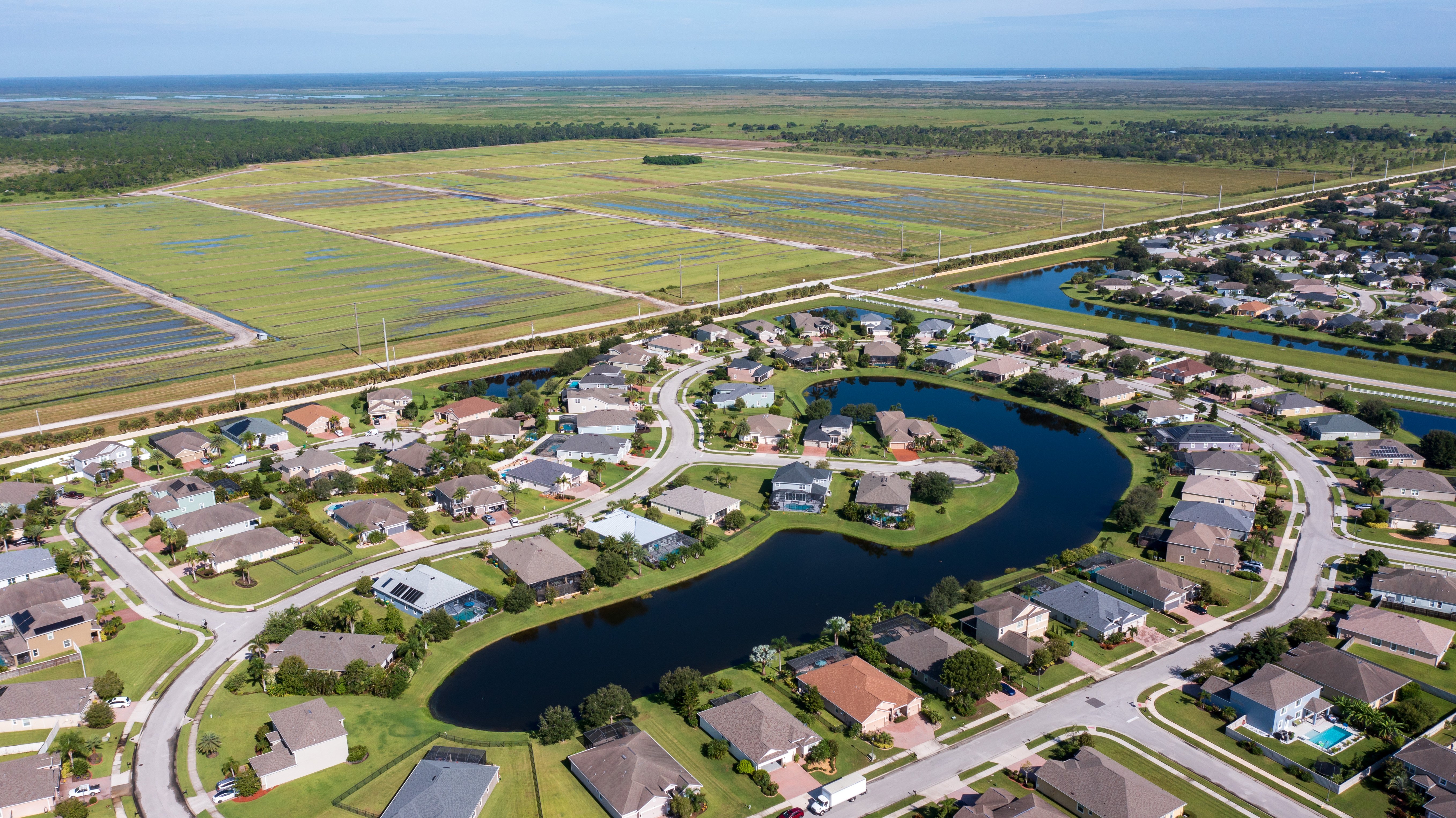 A drone photograph shows a master-planned community and a sod farm in
                            the background near the Indian River Lagoon.